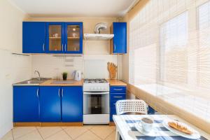 uma pequena cozinha com armários azuis e uma mesa em Apart-Comfort Dresden em Yaroslavl