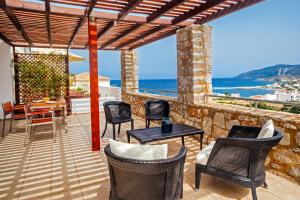 a patio with chairs and tables and a view of the ocean at Kythea Resort in Agia Pelagia