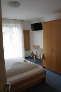 a bedroom with a bed and a tv and a table at Pension Pernthaler in Silandro