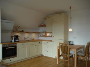 a kitchen with white cabinets and a table with chairs at Ferienwohnung Passivhaus "Schöne Aussicht" in Georgensgmünd