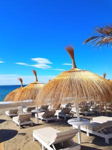 a group of straw umbrellas and chairs on a beach at Gran Hotel Guadalpín Banus in Marbella