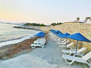 una fila de sillas con sombrillas azules en una playa en Sunset Mavi, en Turgutreis