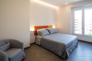 a bedroom with a bed and a chair and a window at Centro storico via Sassari Accommodation in Cagliari