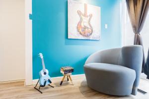 a blue living room with a chair and a guitar at Place des Arts by Hébergements DCL in Quebec City
