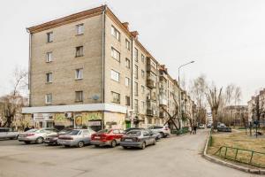 a large brick building with cars parked in a parking lot at Apartment on 50 let Oktyabrya 51 TyumGNGU in Tyumen