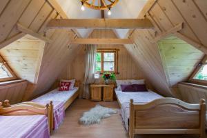 two beds in a attic bedroom with wooden ceilings at Domek Szałas pod Dębem in Ząb