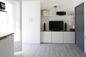 a white living room with a television and white cabinets at GregBnb - Studio Terrasse - PARKING INCLUS - CLIMATISÉ - 15min Gare in Toulon