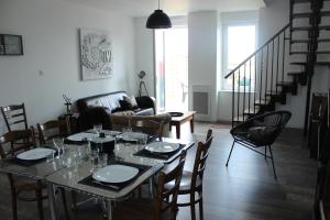 a dining room with a table and chairs and a couch at A chacun son nid in Les Épesses