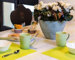 Casa Beatrice في بيلا: طاولة مع كوبين خضراء و مزهرية مع الزهور