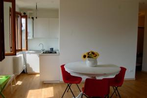 a white kitchen with a white table and red chairs at Casa Patrizia in Sueglio