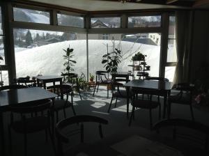a room with tables and chairs and a snow covered wall at Hakuba Alpine Hotel in Hakuba