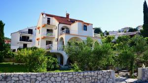 ein großes weißes Haus mit einer Steinmauer in der Unterkunft Apartmani Laura in Trogir