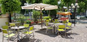 eine Gruppe von Tischen und Stühlen unter einem Sonnenschirm in der Unterkunft Hotel La Falena in Cervia