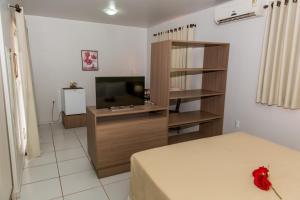 a bedroom with a bed and a television in a room at Pousada Villamor - Naturista Liberal (Adult Only) in Jacumã