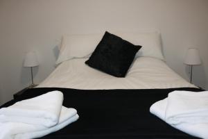 ハリファックスにあるMoorside Lodgeのベッド(白いシーツ、黒い枕付)