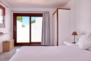 a white bedroom with a bed and a window at Can Mares in Cala Tarida +34 photos