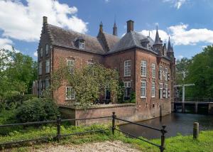 a large brick building with water in front of it at B&B Kasteel Maurick in Vught