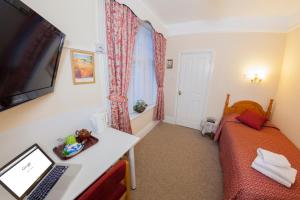 a room with a bed and a desk with a laptop at Gatwick Turret Guest House in Horley