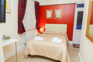 a small bedroom with a bed with red walls at Gatwick Turret Guest House in Horley
