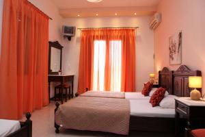 a bedroom with two beds and a window with orange curtains at Maria Studios in Neo Klima