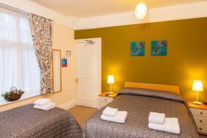 a bedroom with two beds and a green wall at Gatwick Turret Guest House in Horley