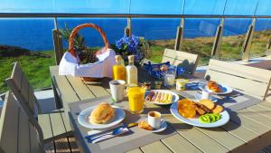 a table with plates of food on it with a view of the ocean at Sao Vicente Lodge - Atlantic Retreat in São Vicente Ferreira