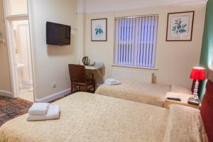 a hotel room with two beds and a television at Gatwick Turret Guest House in Horley