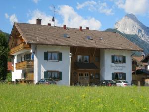 a house in a field with a mountain in the background at Ferienapartmenthaus Hubertushof in Mittenwald