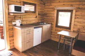 a kitchen in a log cabin with a table and a microwave at Miegalius in Šventoji