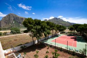 un campo da tennis con alberi e montagne sullo sfondo di Boa Vista San Vito - Area Fitness, Barbecue Area, Tennis Court a San Vito lo Capo