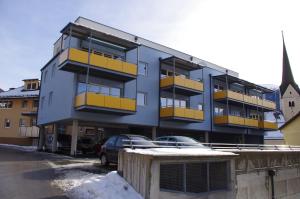 a blue building with yellow balconies and a parking lot at Penthaus Appartement in Sankt Michael im Lungau