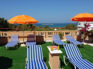 two chairs and a table and an umbrella on a lawn at Ilona Apartments Chania in Kato Daratso