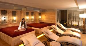 a woman sitting on a bed in a room with chairs at Residence St Konstantin in Fiè