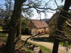 una casa con un árbol delante de ella en Gîte La Borie Basse, en Léobard