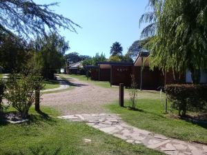 a dirt road in a yard with trees and a house at Brisas Del Rio Apart Hotel in Termas del Daymán