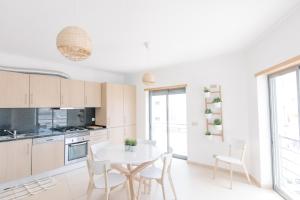 Una cocina blanca con una mesa y sillas blancas. en Casas de Mar - Barco, en Olhão