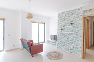 sala de estar con silla y mural en la pared en Casas de Mar - Barco, en Olhão