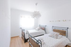 Un dormitorio con dos camas y una lámpara de araña. en Casas de Mar - Barco, en Olhão