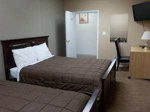 a hotel room with two beds and a desk and a television at Vernon Hostel in Vernon