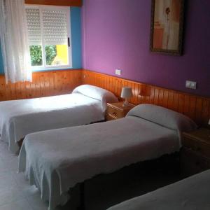 ソティージョ・デ・ラ・アドラダにあるHostal El Veneroの紫の壁のベッドルーム1室(ベッド3台付)