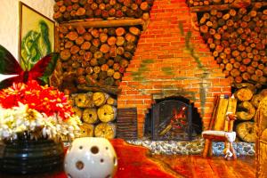 a living room with a brick fireplace and a pile of logs at Finca Campestre La Adelita B&B in Salento