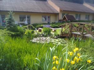 un jardín con un puente y un estanque con flores en Ośrodek Wczasowy "GRONOSTAJ" en Rajcza