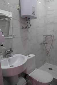 a white bathroom with a sink and a toilet at Elida in Gagra