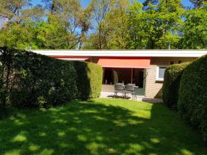 a house with hedges in front of a yard at Knusse Natuur Bungalow Hartje Veluwe in Otterlo