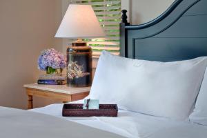 a bed with a white pillow and a table with a lamp at White Elephant Hotel in Nantucket