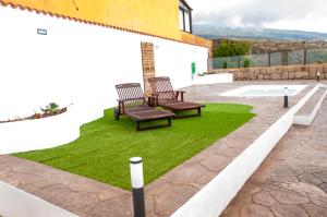 two benches on a patio with green grass at MARCELA&JOAQUIN MOUNTAIN HOUSE in Fasnia