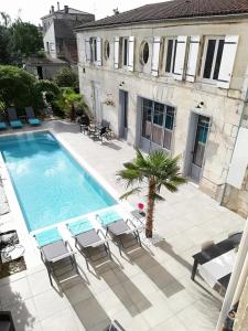 - une piscine avec des chaises et une maison dans l'établissement L'Angély - Chambres d'Hôtes, à Niort