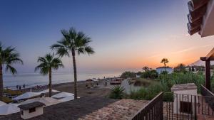 マルベーリャにあるThe Residence by the Beach House Marbellaのヤシの木が植えられた夕日のビーチの景色