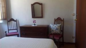 a bedroom with a bed and two chairs and a mirror at Pensao Avenida in Caldelas