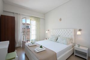 a white bedroom with a large bed and a window at The Orange Garden in Kassiopi